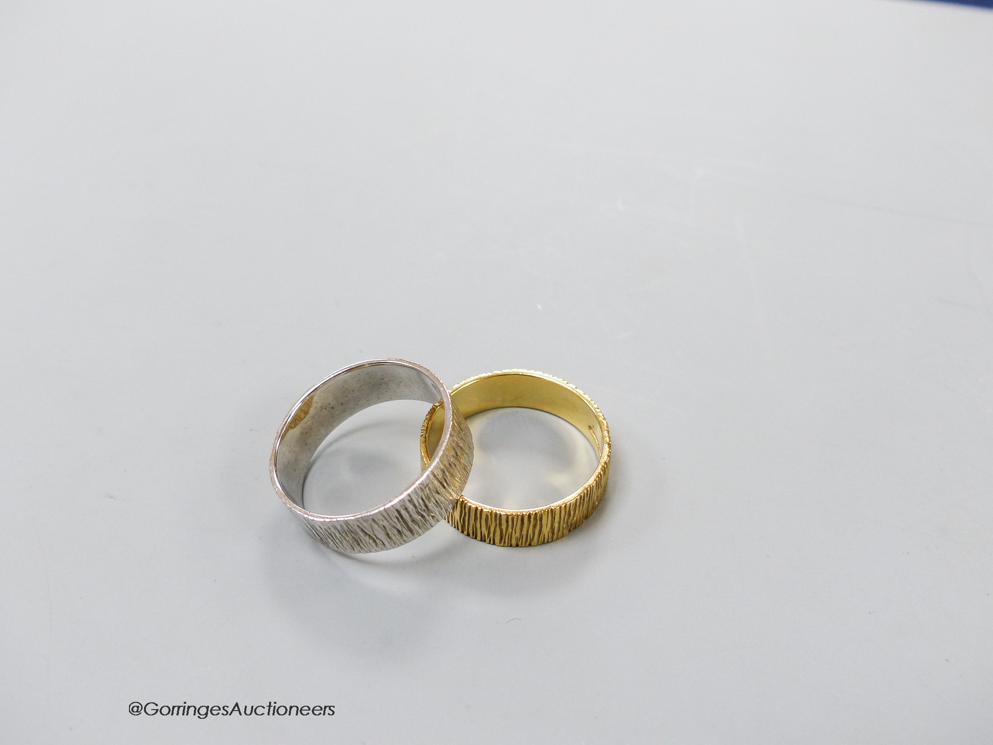 A modern textured 18ct gold band, size S, 5 grams and a similar 9ct white gold band, size S, 4.7 grams.